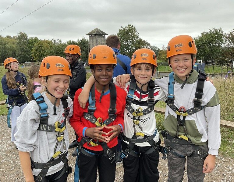 four kids wearing orange helmets and harnesses