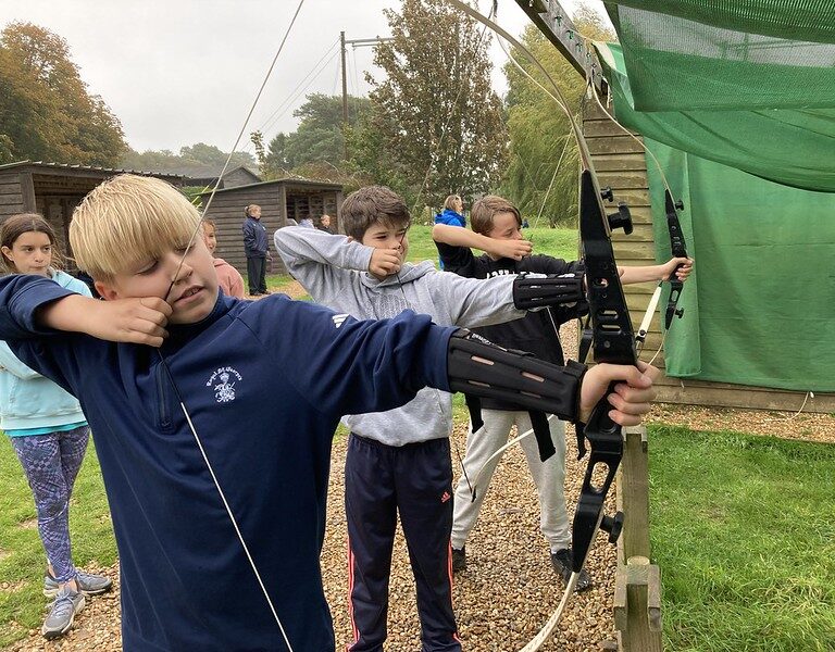kids in a row practising archery