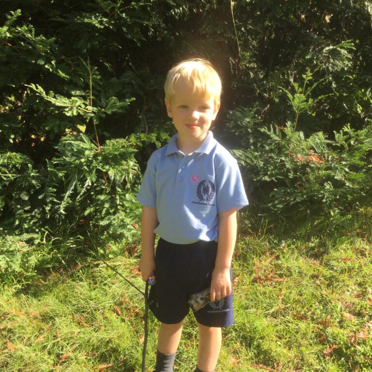 little boy outside holding a big twig