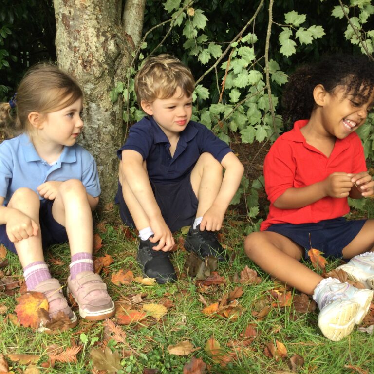 3 young kids sitting on the grass